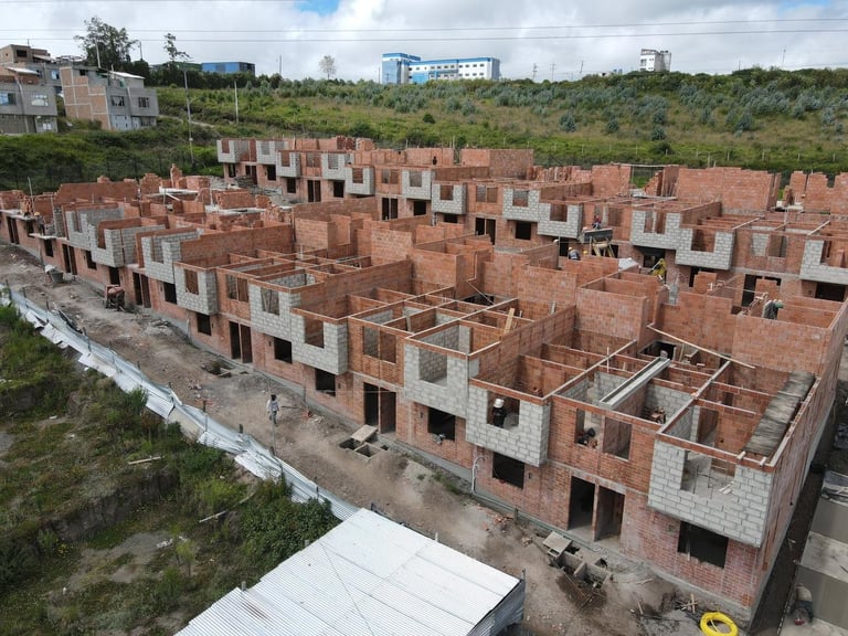 Aerial view of an under-construction residential neighborhood with red brick buildings on a hillside